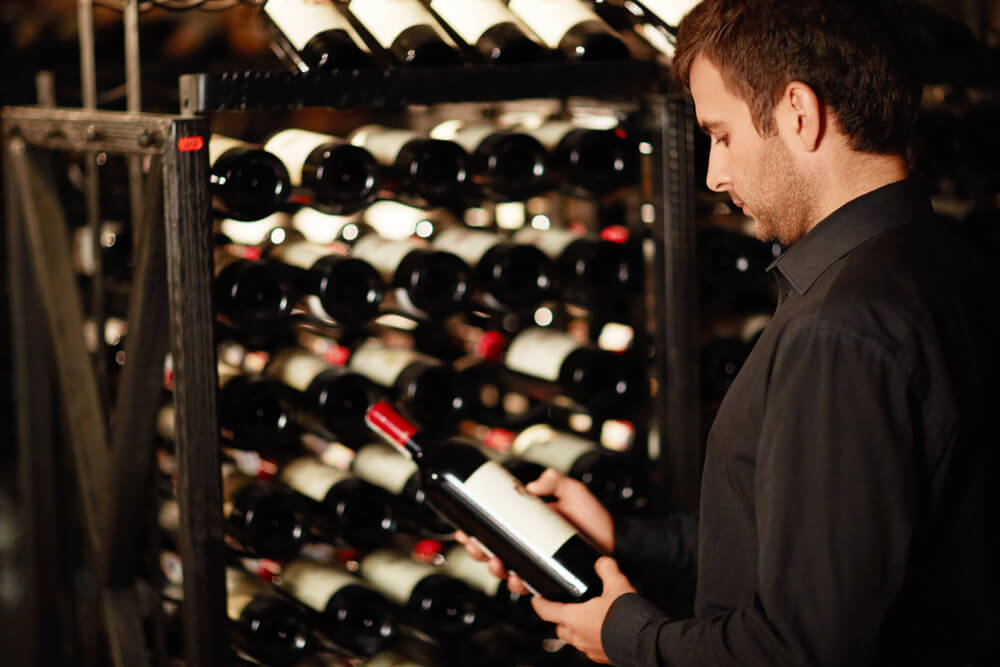 man selecting a wine off of a wine rack