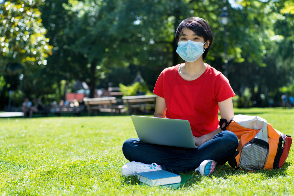 male student with face mask at campus of university in summer