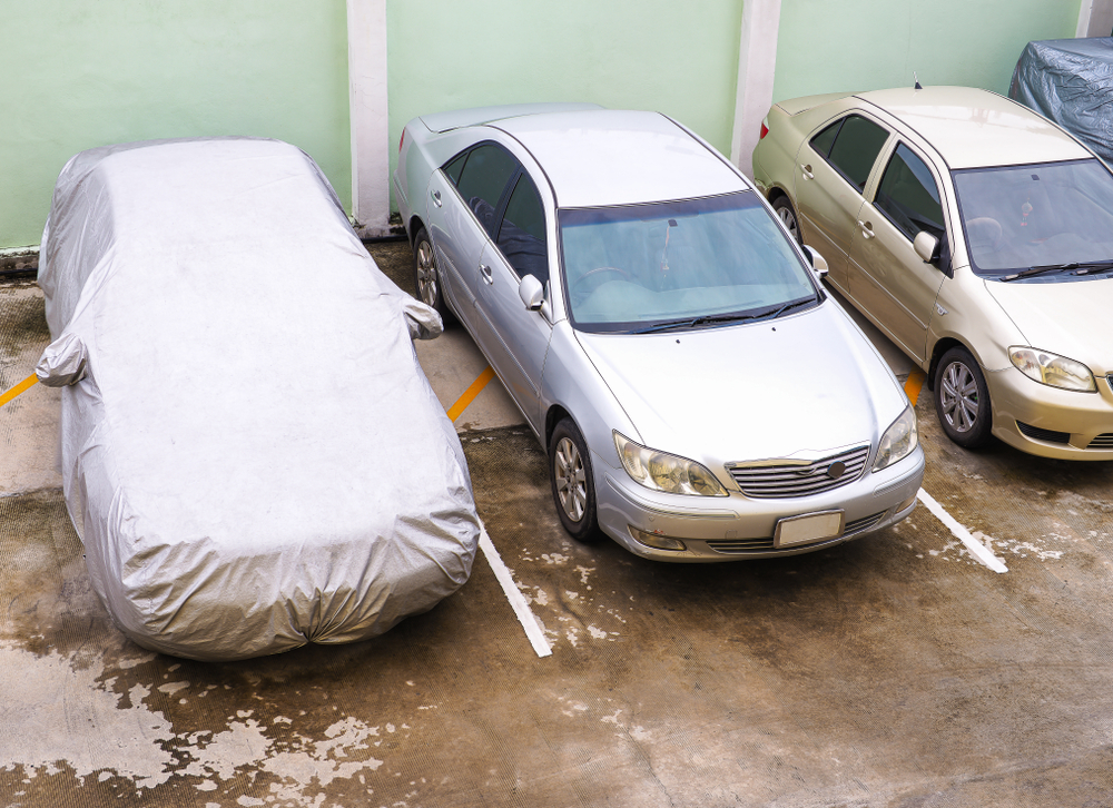 multiple cars lined up with one having a car cover on