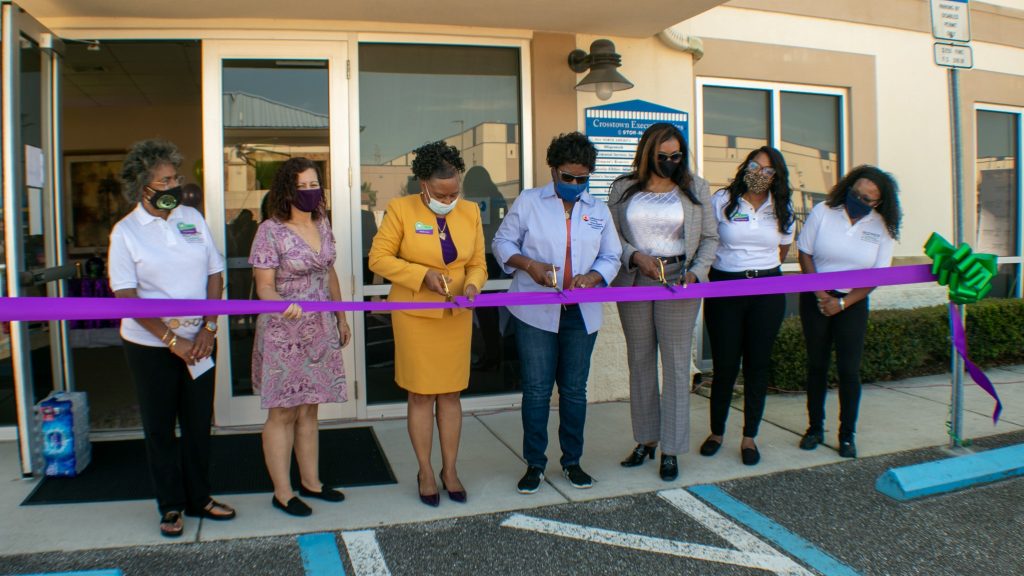 Women cutting ribbon in front of business